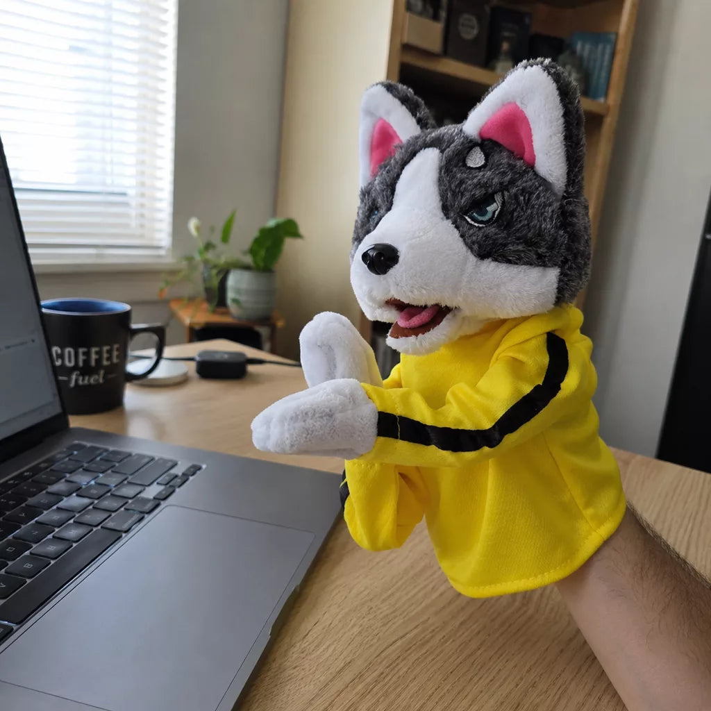 The husky puppet mid jab next to a laptop at an office desk